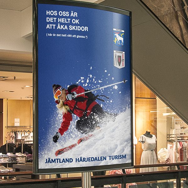 Storbildsoriginal till turistverksamhet. En kvinna i röd jacka som åker skidor.